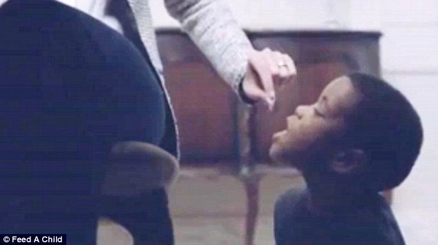 childchild is seen below the dining room table getting fed by the woman like a dog