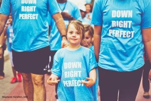 A child with Down's Syndrome wearing a shirt that says "Down Right Perfect."