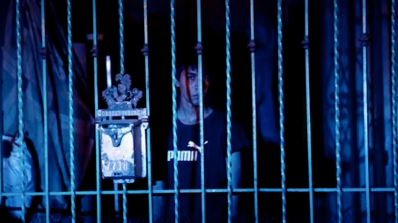 Person standing behind bars, blue overtones