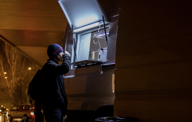 Person standing at open window of a store