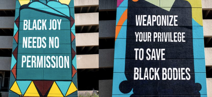 Two wall murals. One says Black Joy Needs No Permissions, the other reads Weaponize Your Privilege to Save Black Bodies 