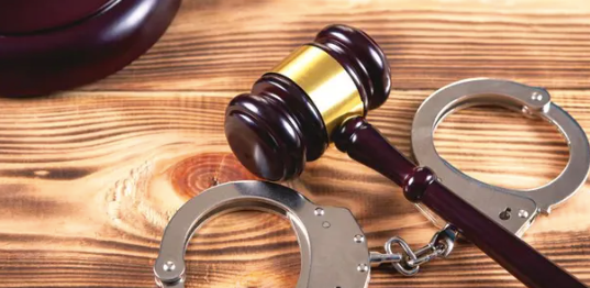 Gavel and handcuffs on wooden background