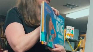 Woman holds up book that is banned in the library