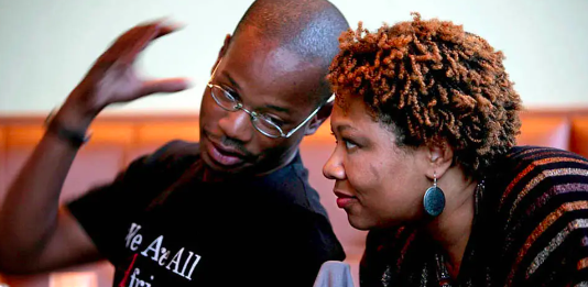 Two Black Individuals talk, one with hand in the air