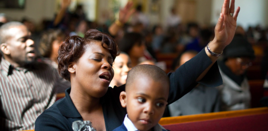 Black family in pews praising God 