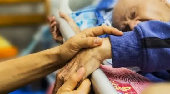 Healthcare provider holding the hand of somebody in the hospital bed. 