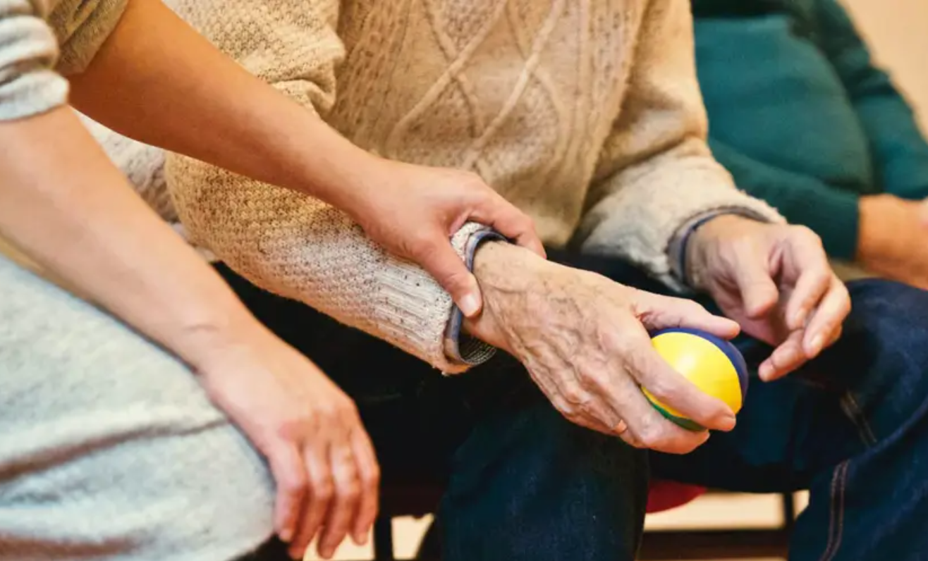 young hand holding older hand with a ball