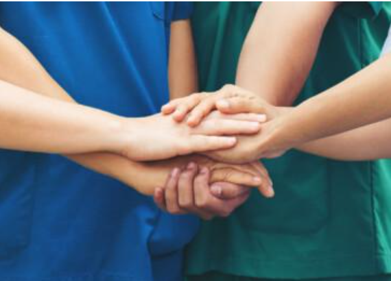 coworkers with their hands stacked on top of each other in a gesture of teamwork