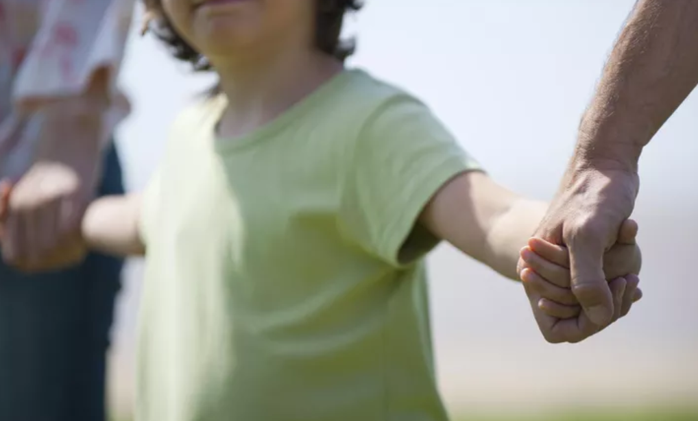 child  holding hands with both parents