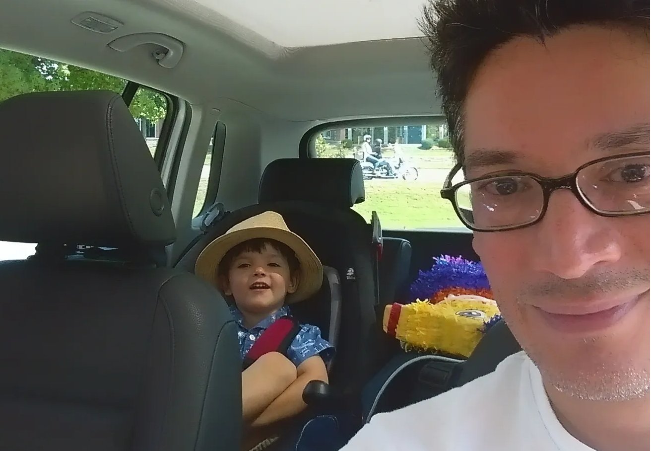 Man taking selfie with child in the backseat of his car