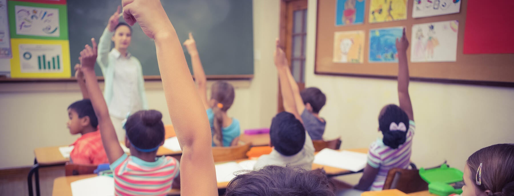 Students in a classroom raising their hands 