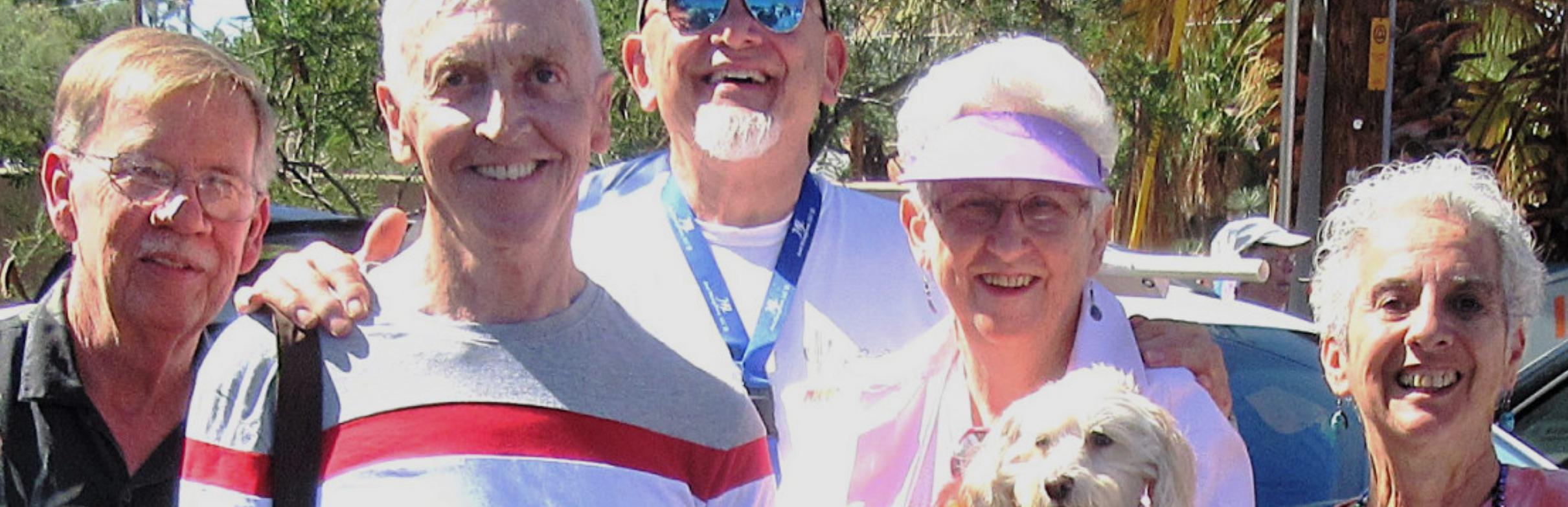 five elderly people stand shoulder to shoulder smiling 