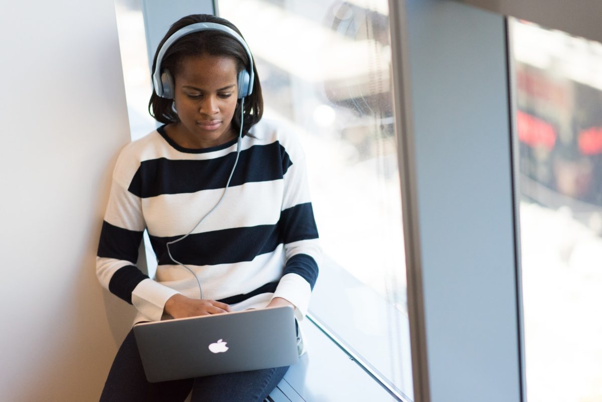 Woman sitting in chair with laptop on lap with large headphones on 