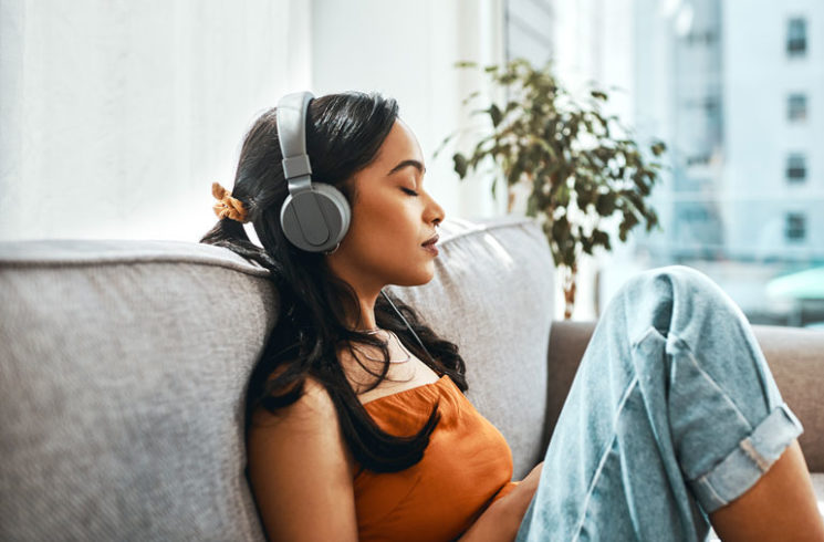 Woman with headphones sitting on couch