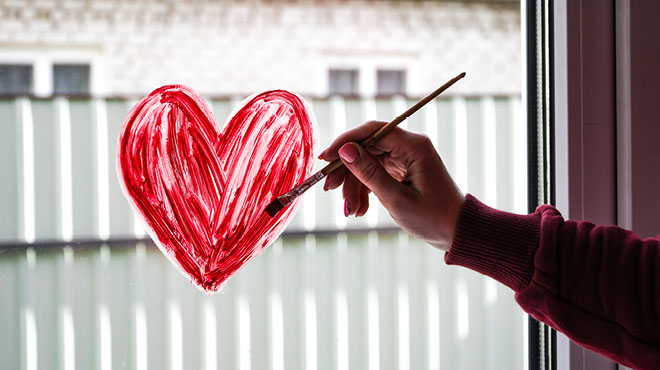 hand painting a heart on a window