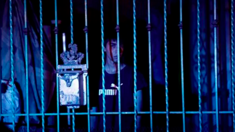 Person standing behind bars, blue overtones